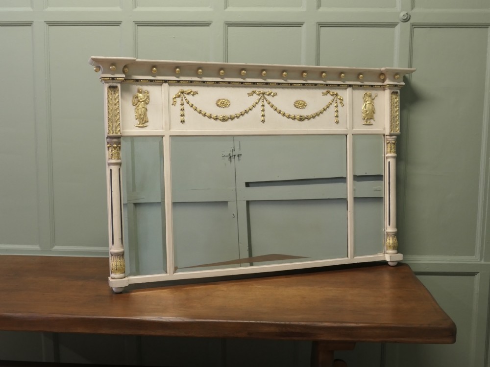 A Regency Neoclassical triple-plate overmantel mirror with off-white painted frame, gold leaf swags, relief figures, and side pilasters. View IV