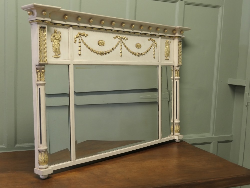 A Regency Neoclassical triple-plate overmantel mirror with off-white painted frame, gold leaf swags, relief figures, and side pilasters. View V
