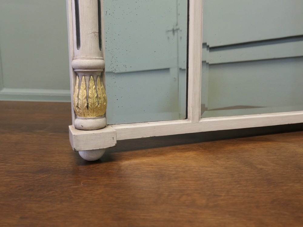 A Regency Neoclassical triple-plate overmantel mirror with off-white painted frame, gold leaf swags, relief figures, and side pilasters. View VII