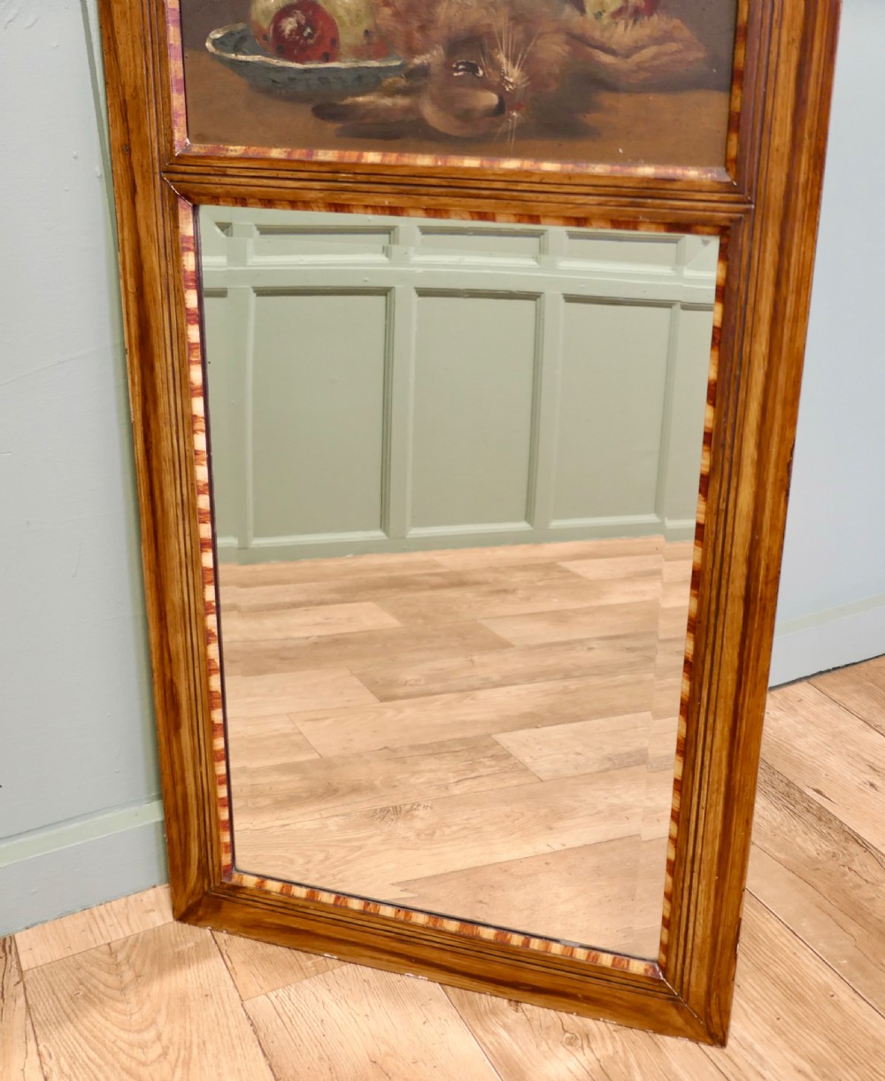 A tall rectangular timber-framed trumeau mirror featuring an inset oil painting of a game still life above a mirror panel. View V