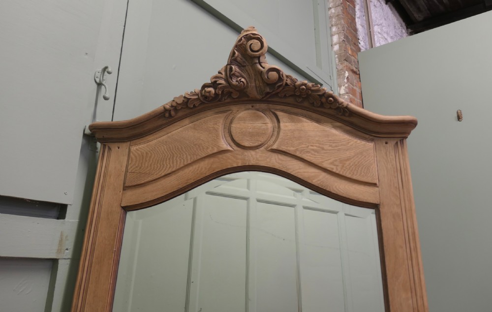 A tall French Provincial style wall mirror with a bleached oak arched frame and a detailed hand-carved floral crest. View IV