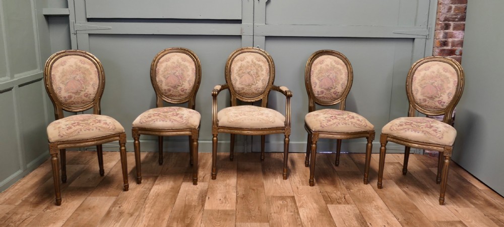 A five-piece French Louis XVI style salon seating set featuring four side chairs and one armchair with gilded frames and floral tapestry upholstery. View II