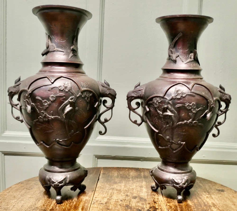 A pair of dark brown Japanese Meiji period bronze vases featuring relief depictions of birds on branches and dragon-shaped handles on footed bases. View II
