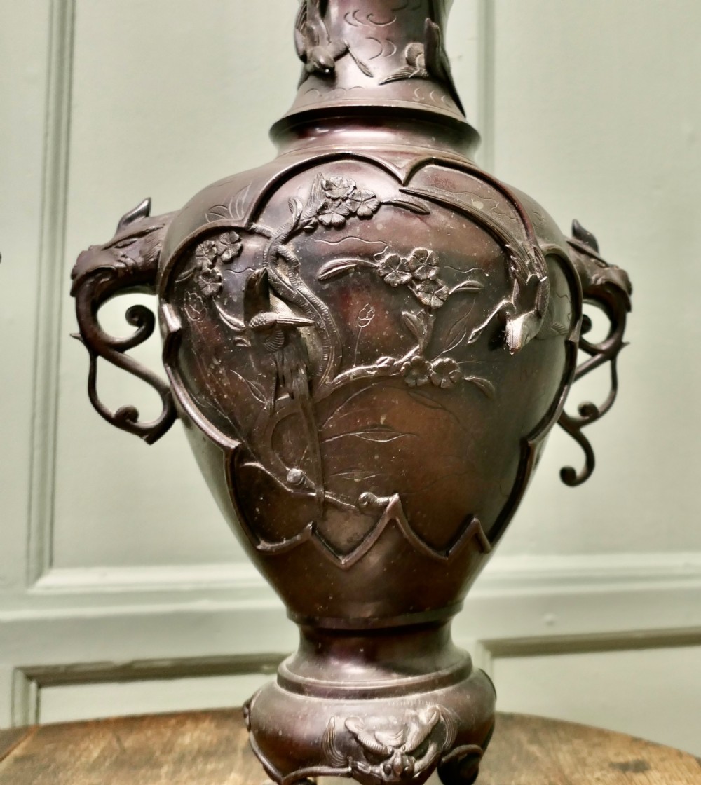 A pair of dark brown Japanese Meiji period bronze vases featuring relief depictions of birds on branches and dragon-shaped handles on footed bases. View III