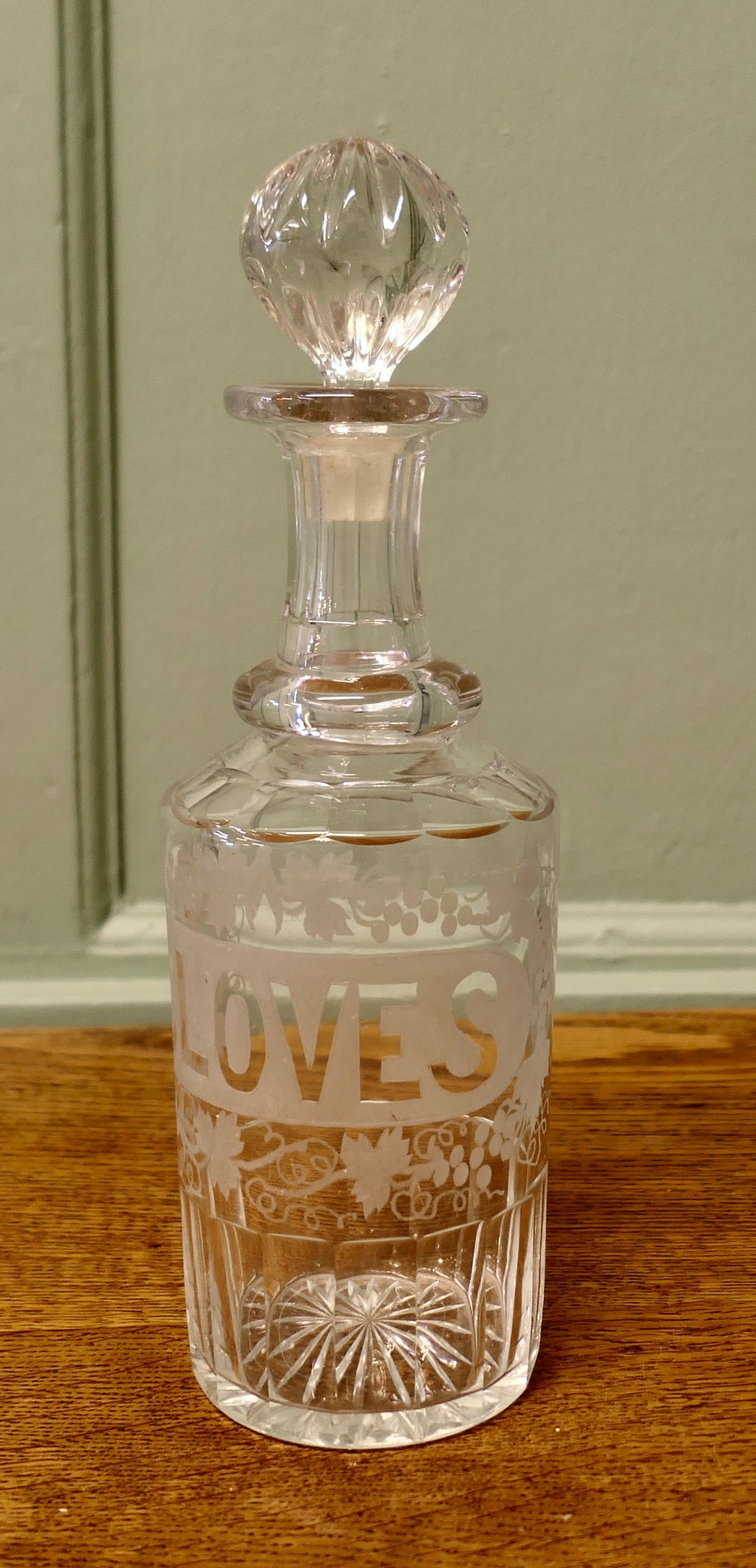 A Victorian clear crystal decanter featuring etched lettering spelling Cloves framed by vine motifs, complete with a fluted neck and faceted glass stopper.