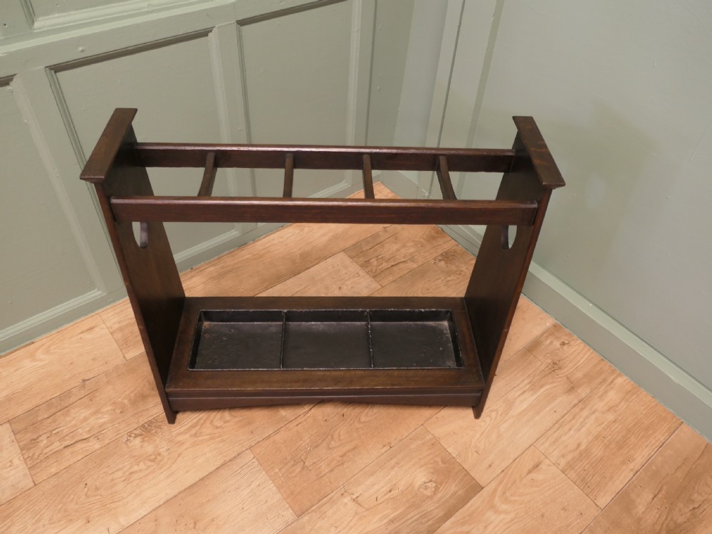 A dark oak Arts and Crafts umbrella stand featuring heart-shaped cutouts on sloped side panels and a metal drip tray at the base. View II