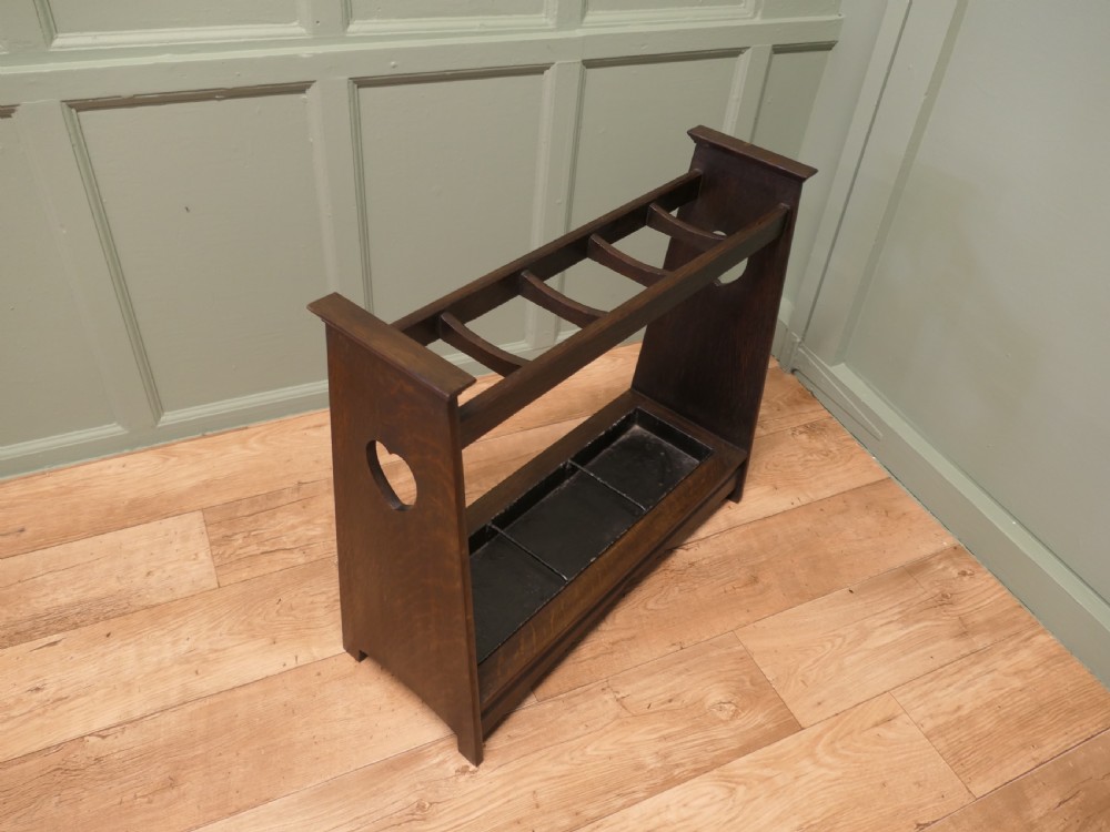 A dark oak Arts and Crafts umbrella stand featuring heart-shaped cutouts on sloped side panels and a metal drip tray at the base. View III