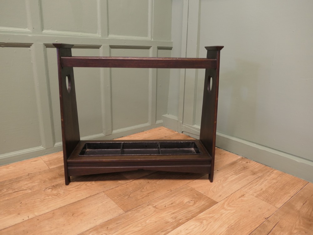 A dark oak Arts and Crafts umbrella stand featuring heart-shaped cutouts on sloped side panels and a metal drip tray at the base. View IV