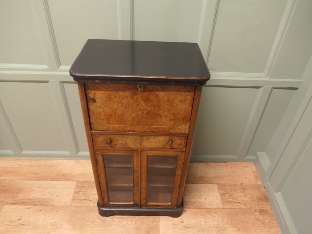 A Victorian burr walnut music filing cabinet featuring a fall-front upper compartment with inlaid details, a central drawer, and double glazed lower doors.