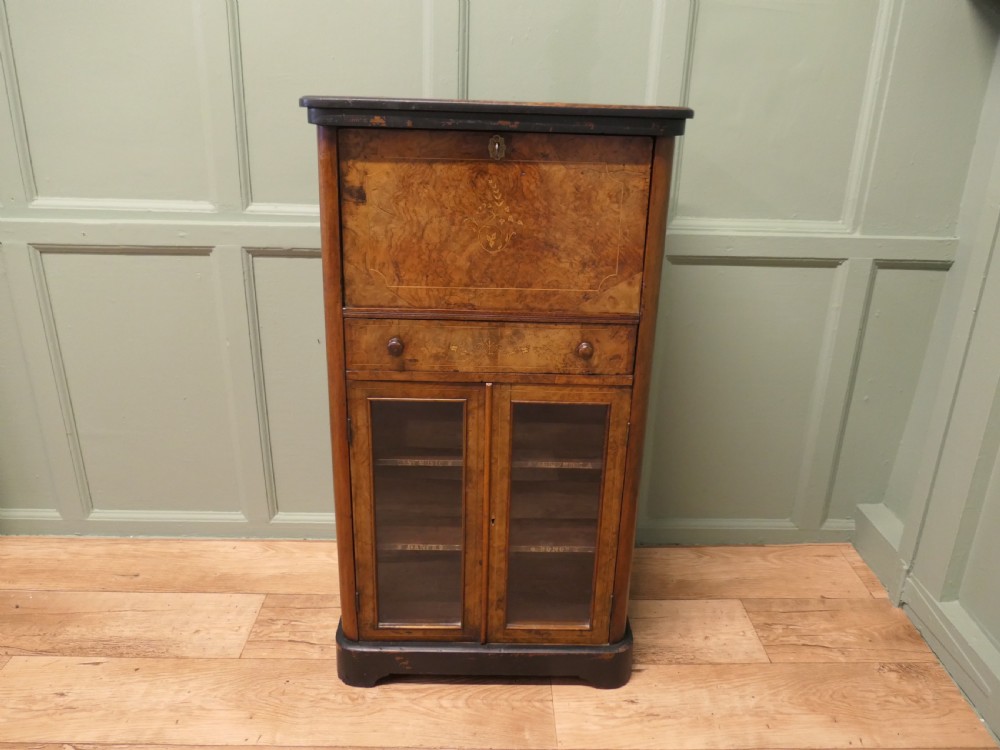 A Victorian burr walnut music filing cabinet featuring a fall-front upper compartment with inlaid details, a central drawer, and double glazed lower doors. View II