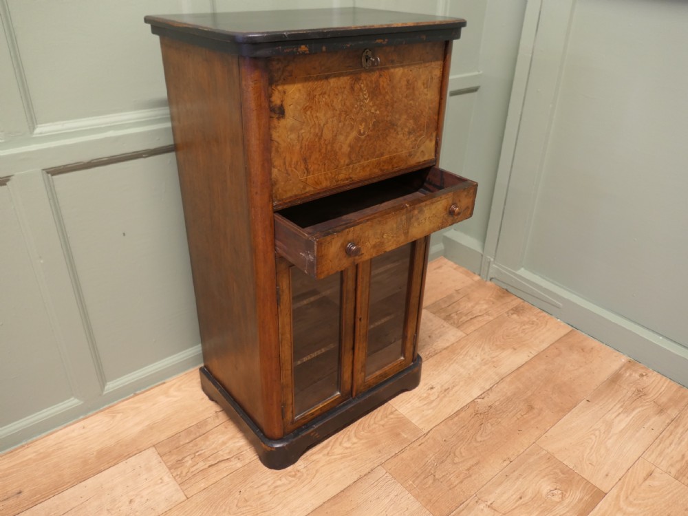 A Victorian burr walnut music filing cabinet featuring a fall-front upper compartment with inlaid details, a central drawer, and double glazed lower doors. View III