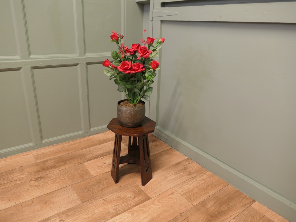 An octagonal Arts and Crafts solid oak plant stand featuring splayed legs with vertical slots and heart cut-outs connected by a lower stretcher. View IV
