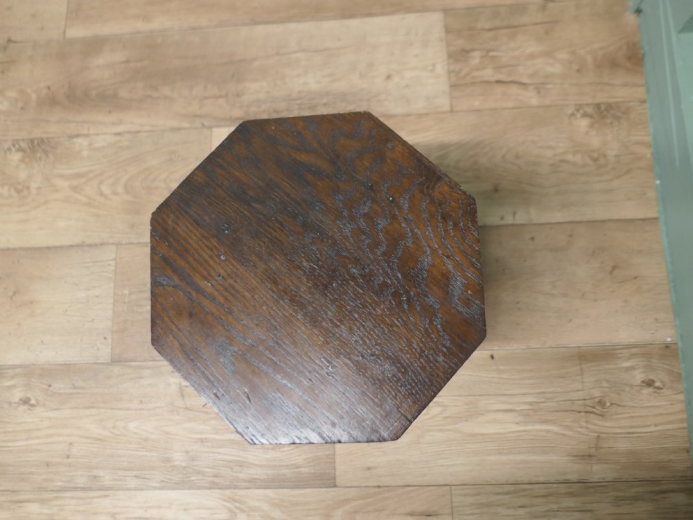 An octagonal Arts and Crafts solid oak plant stand featuring splayed legs with vertical slots and heart cut-outs connected by a lower stretcher. View V