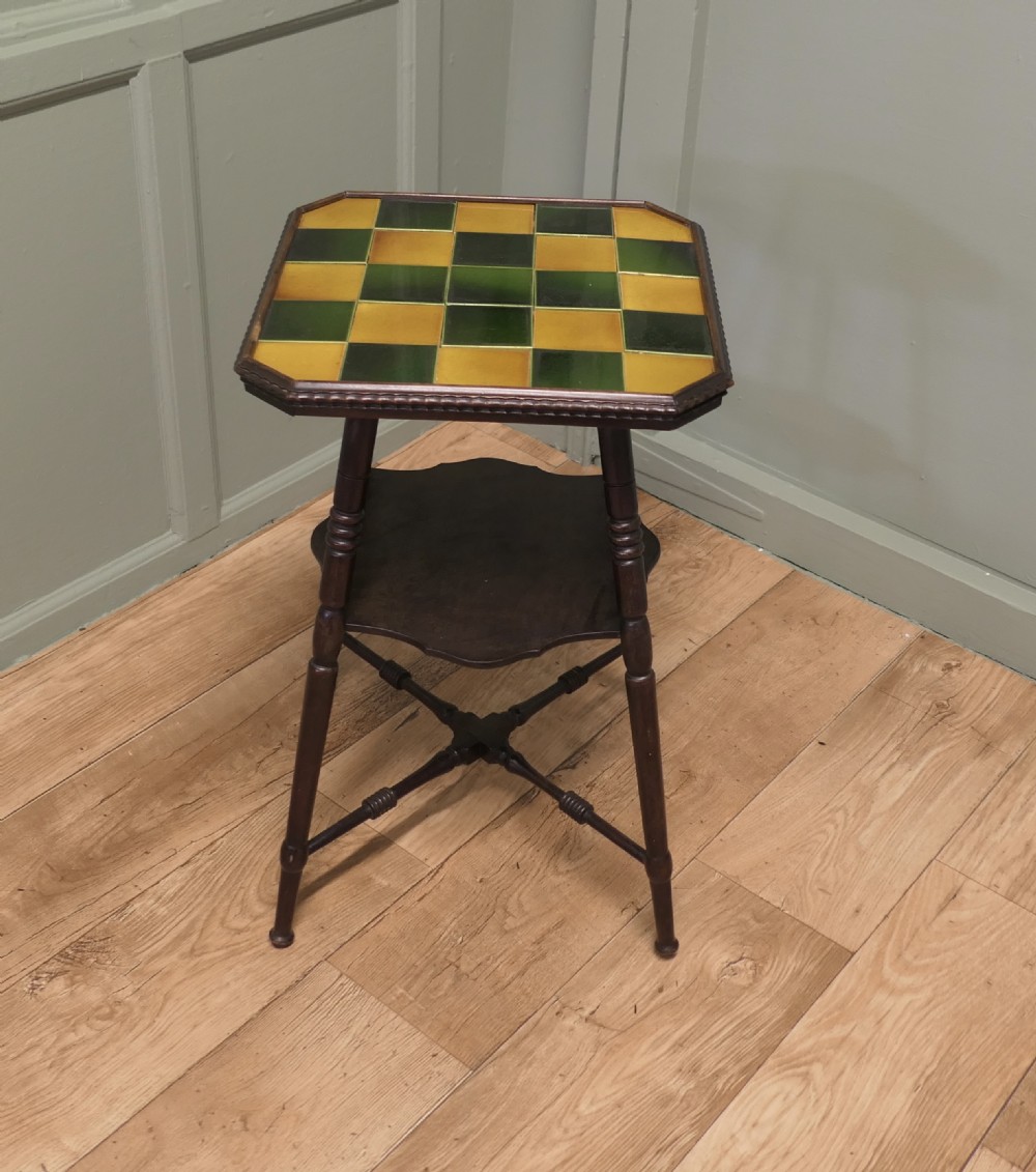 An Arts and Crafts dark wood side table with a chequerboard top made of green and yellow glazed ceramic tiles, turned legs, and an undertier. View III