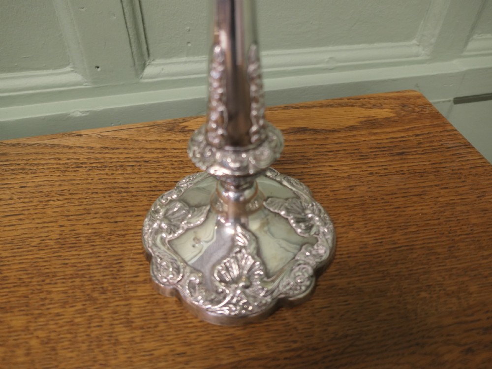 A pair of 19th-century silver-plated candlesticks featuring floral relief details on the shaped bases and tapered stems. View II