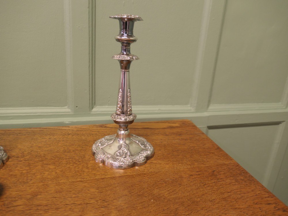 A pair of 19th-century silver-plated candlesticks featuring floral relief details on the shaped bases and tapered stems. View IV