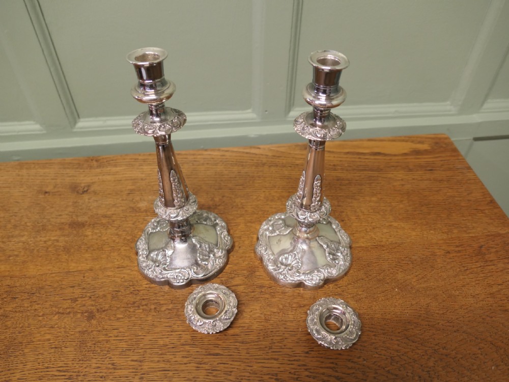 A pair of 19th-century silver-plated candlesticks featuring floral relief details on the shaped bases and tapered stems. View VI