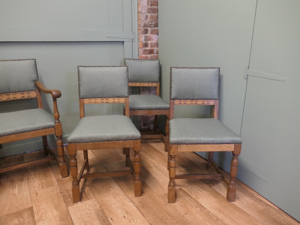 A set of eight Arts and Crafts golden oak dining chairs with upholstered seats and backrests trimmed with brass studs. View II