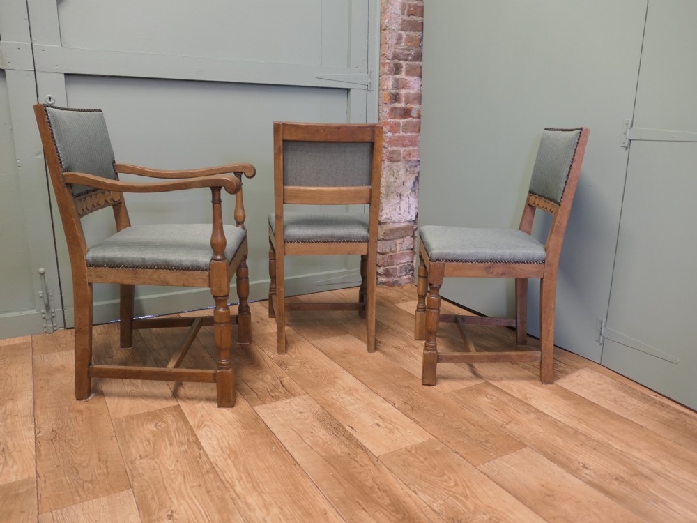 A set of eight Arts and Crafts golden oak dining chairs with upholstered seats and backrests trimmed with brass studs. View V