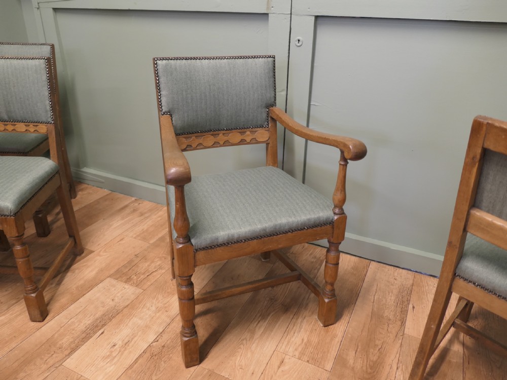 A set of eight Arts and Crafts golden oak dining chairs with upholstered seats and backrests trimmed with brass studs. View VI