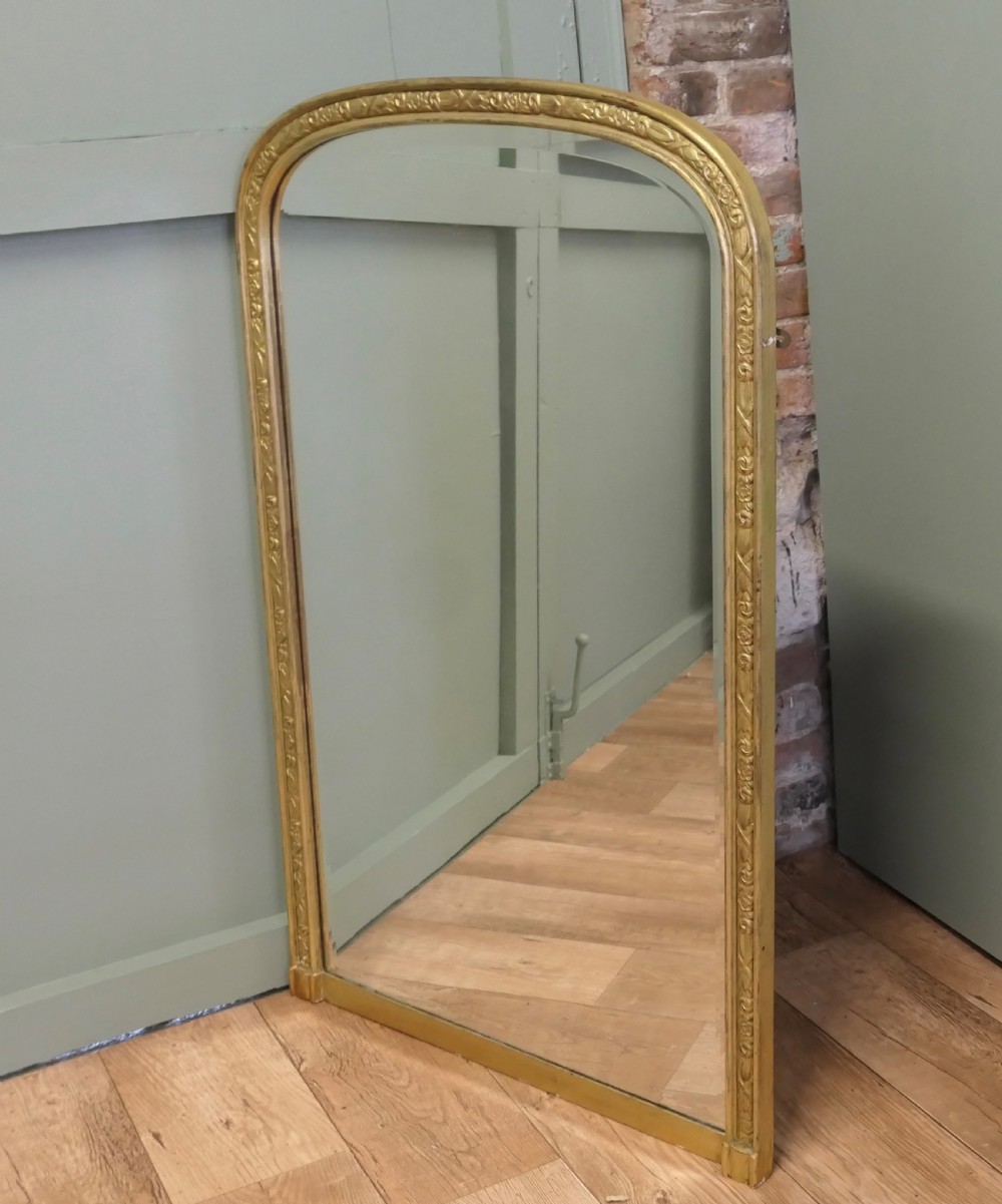 A tall 19th-century French Louis Philippe wall mirror featuring rounded upper corners and an engraved gold gilded frame. View IV