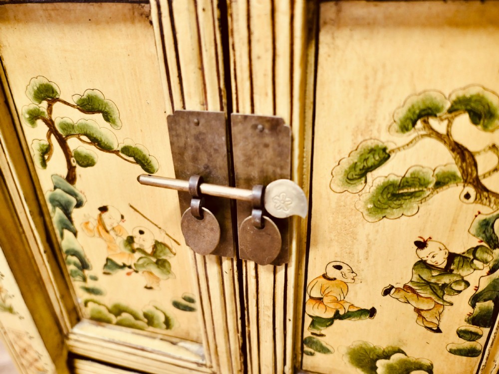 A nineteenth-century cream painted wooden Chinoiserie cabinet featuring two doors illustrated with Asian figures, foliage, decorative borders, and a brass pin closure. View III