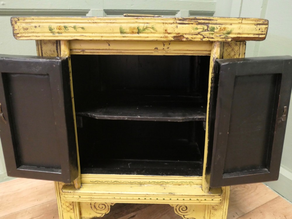 A nineteenth-century cream painted wooden Chinoiserie cabinet featuring two doors illustrated with Asian figures, foliage, decorative borders, and a brass pin closure. View VI