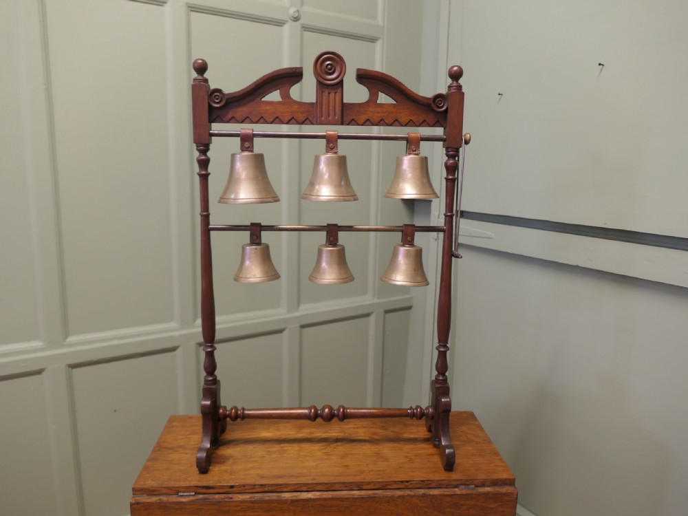 A Victorian carved walnut rack displaying six tuned brass bells arranged across two horizontal tiers on turned wooden uprights. View III