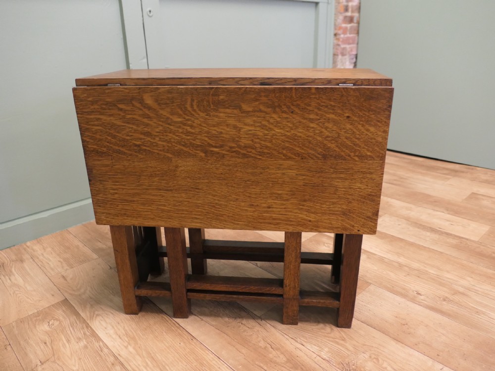 An Arts and Crafts golden oak drop-leaf dining table with pierced cutout side panels. View VI