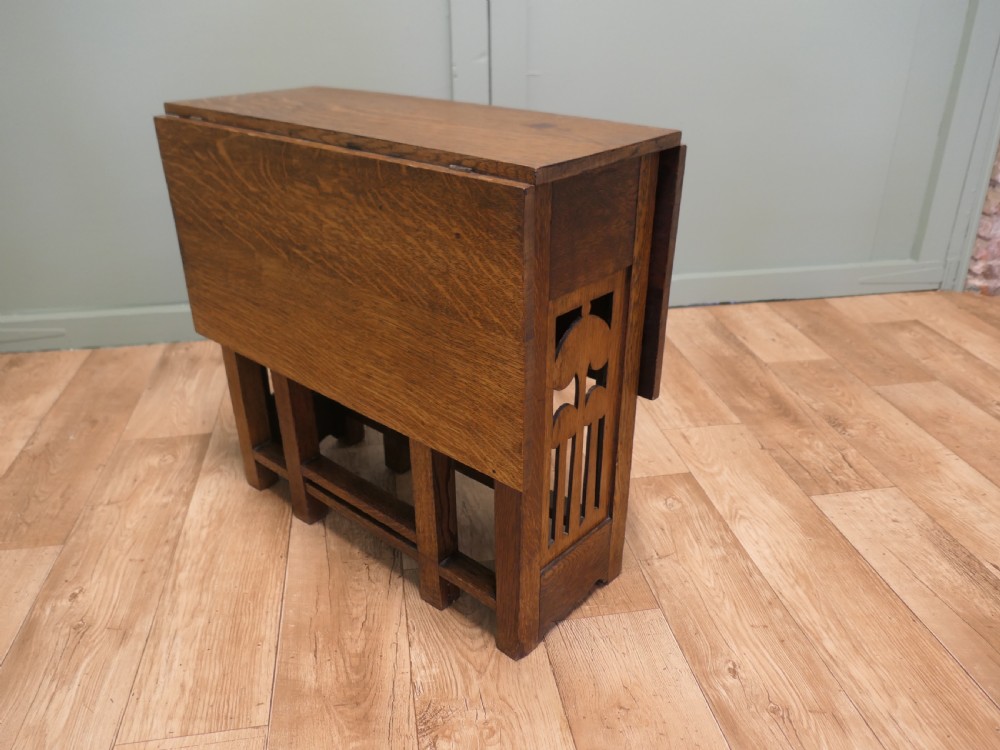 An Arts and Crafts golden oak drop-leaf dining table with pierced cutout side panels. View VII