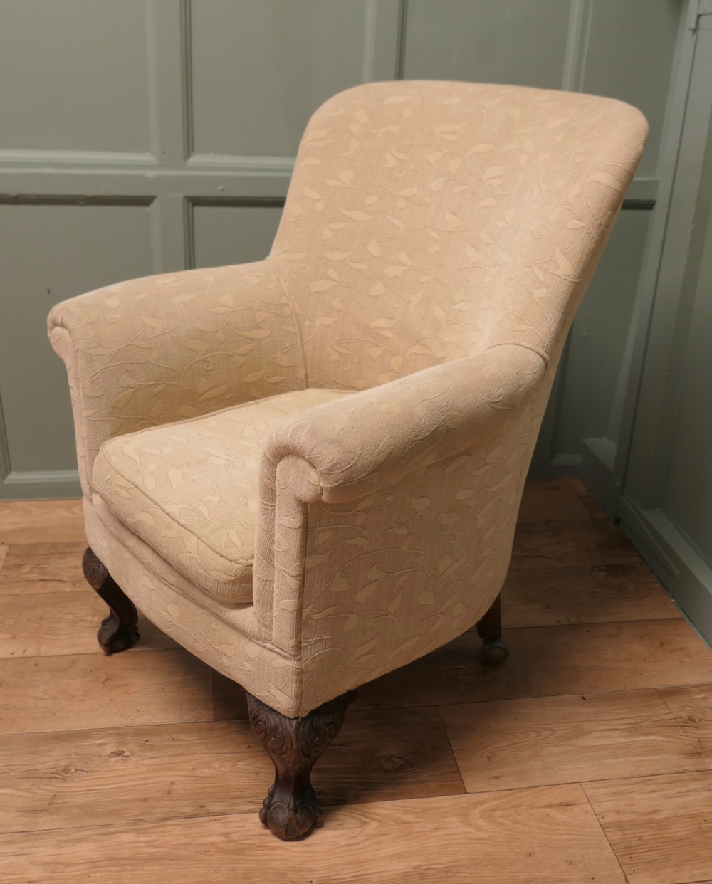 A Victorian upholstered tub armchair in cream patterned fabric with carved timber legs.