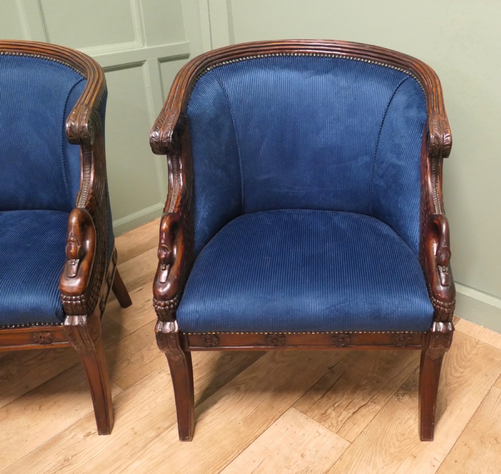 A pair of Victorian tub chairs with blue upholstery and carved mahogany frames featuring carved swan neck armrests. View IV