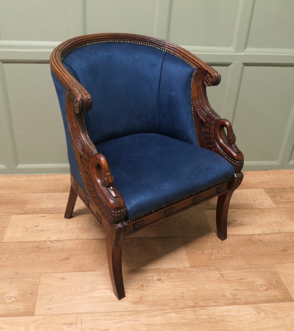 A pair of Victorian tub chairs with blue upholstery and carved mahogany frames featuring carved swan neck armrests. View V