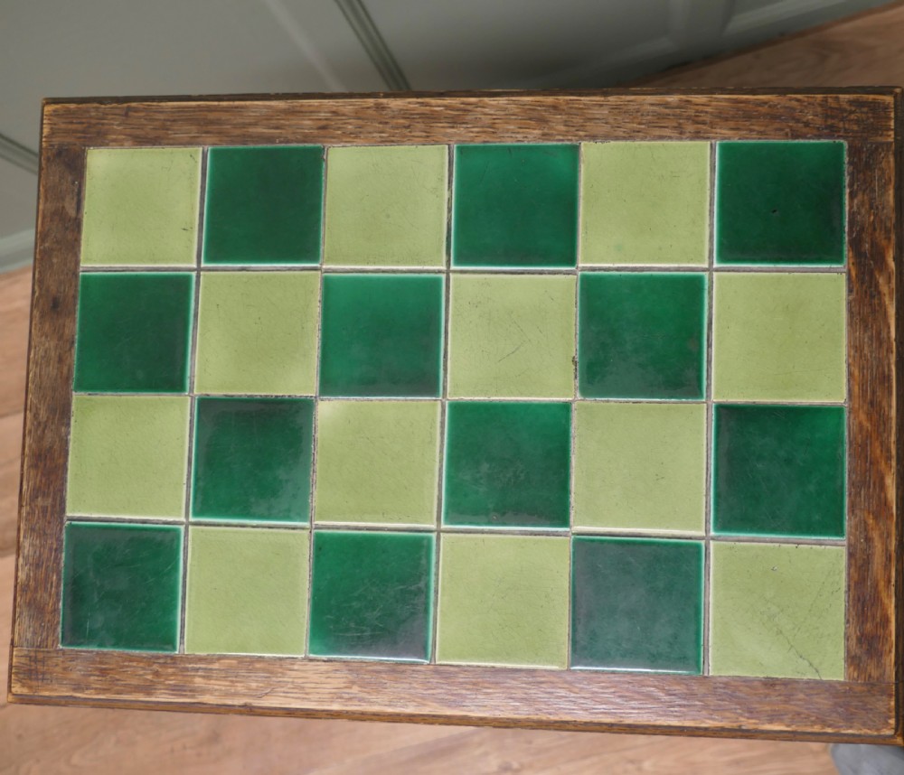 An Arts and Crafts oak occasional table featuring a green checkerboard ceramic tiled top, tapered legs, and heart-shaped cutouts on the apron. View II