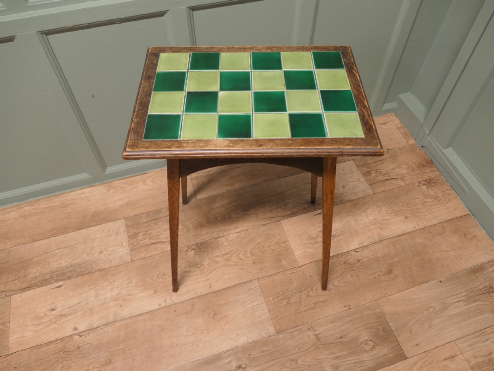 An Arts and Crafts oak occasional table featuring a green checkerboard ceramic tiled top, tapered legs, and heart-shaped cutouts on the apron. View III