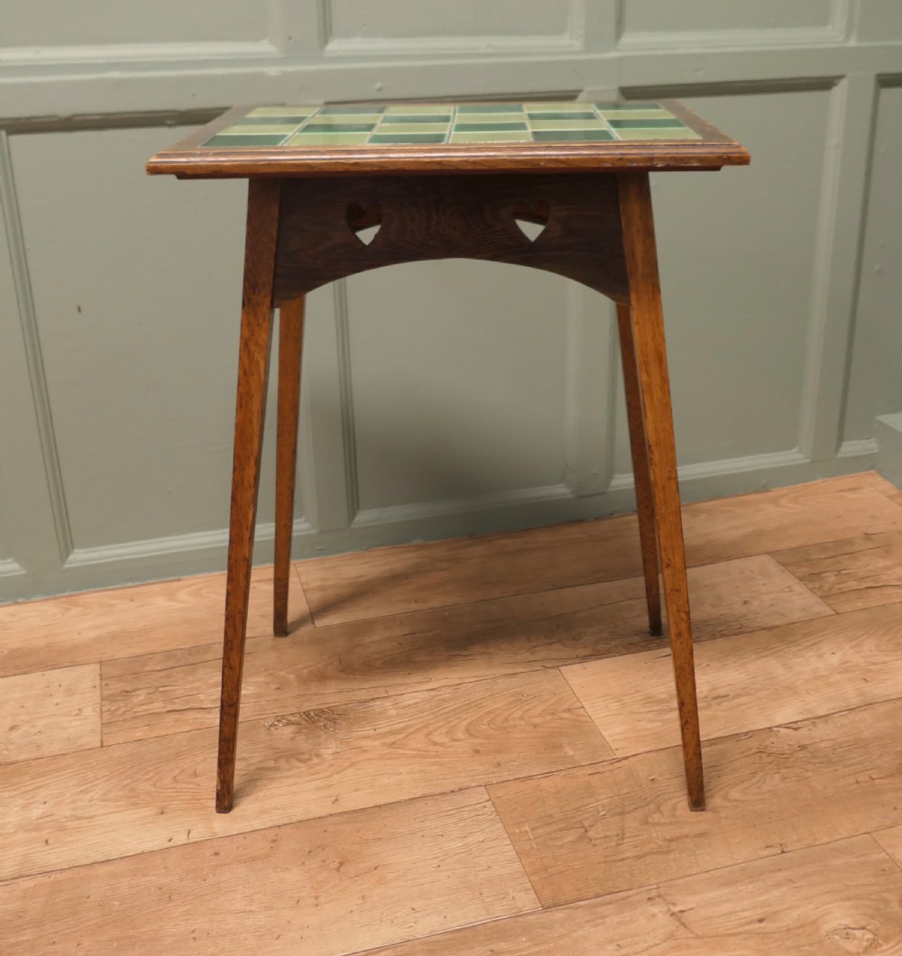An Arts and Crafts oak occasional table featuring a green checkerboard ceramic tiled top, tapered legs, and heart-shaped cutouts on the apron. View VI