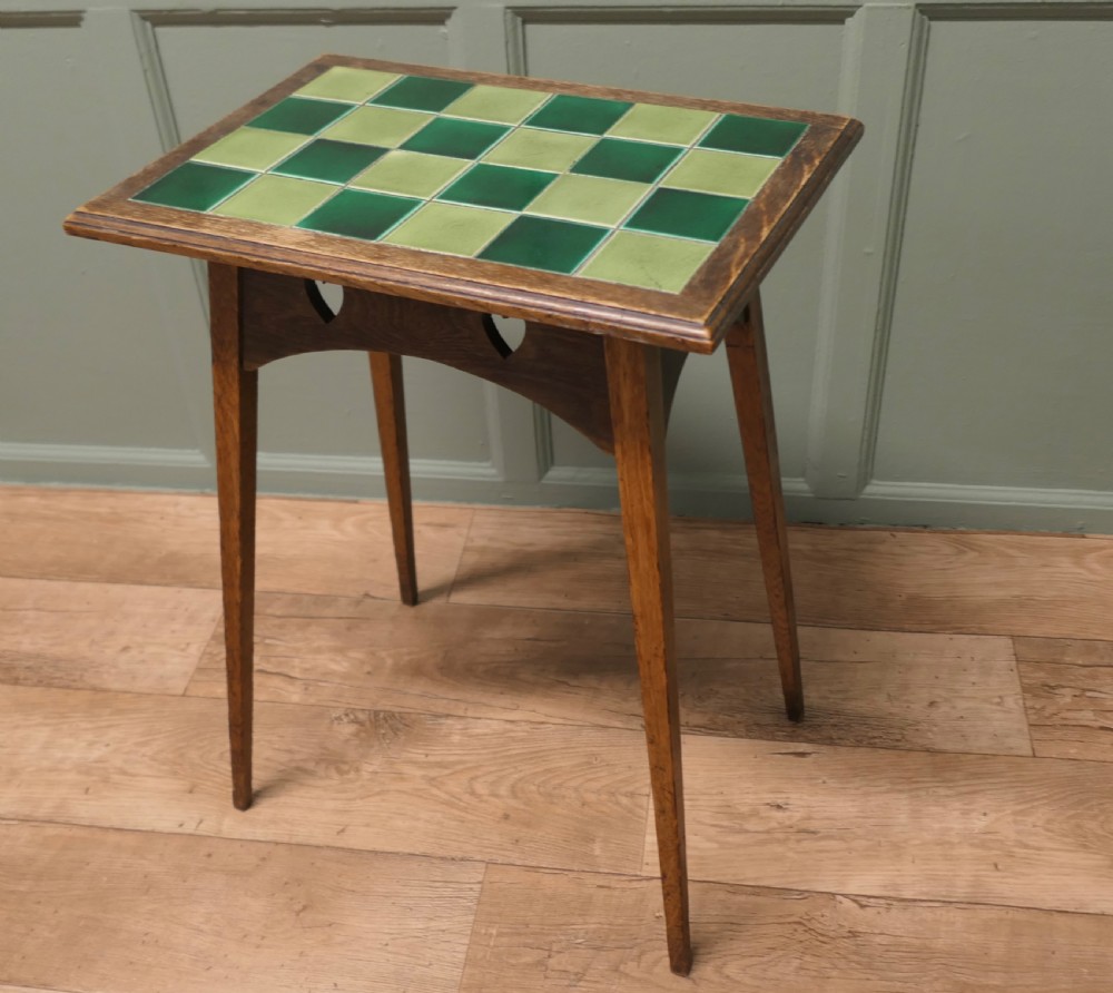 An Arts and Crafts oak occasional table featuring a green checkerboard ceramic tiled top, tapered legs, and heart-shaped cutouts on the apron. View VII