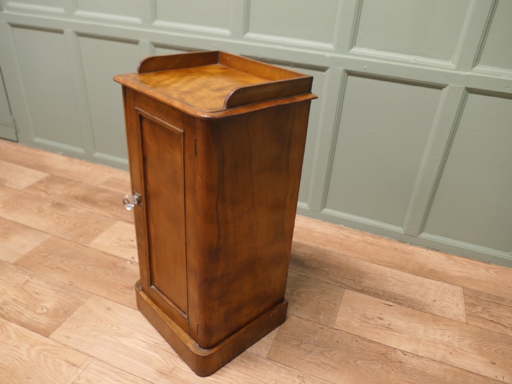 A Victorian birch bedside cupboard featuring a three-sided gallery top, a single panelled door with a glass handle, and a solid plinth base. View II