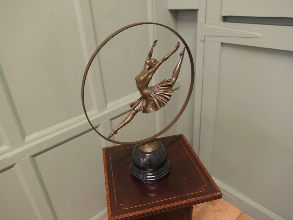 A bronze sculpture depicting a ballerina leaping inside a circular hoop, mounted on a turned black marble base. View V