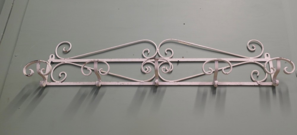 A long, wall-mounted off-white wrought iron hat and coat rack featuring scrollwork detailing and multiple curved hooks. View II