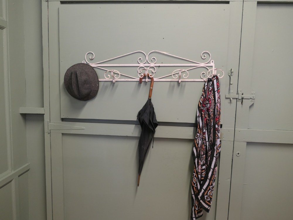 A long, wall-mounted off-white wrought iron hat and coat rack featuring scrollwork detailing and multiple curved hooks. View III