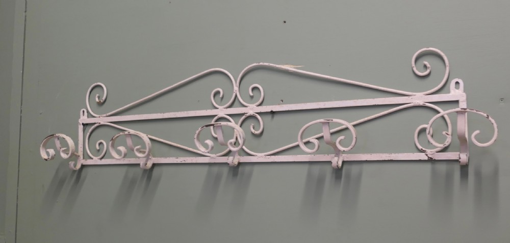 A long, wall-mounted off-white wrought iron hat and coat rack featuring scrollwork detailing and multiple curved hooks. View IV