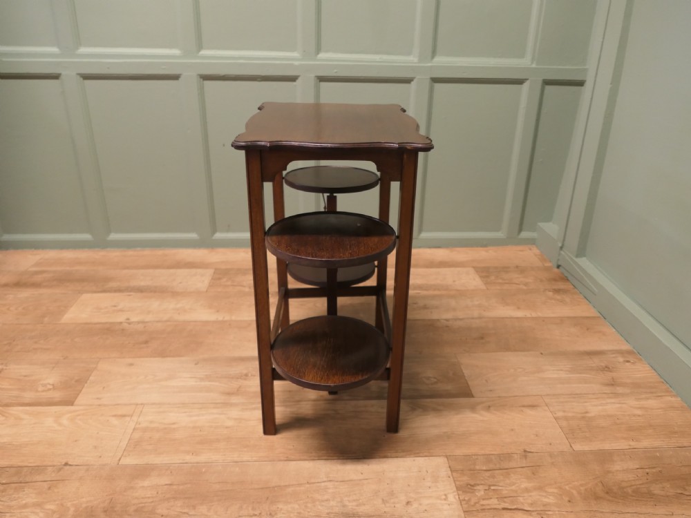 An Edwardian mahogany side table featuring a flat rectangular top and two side-mounted folding circular tiered cake stands. View VI