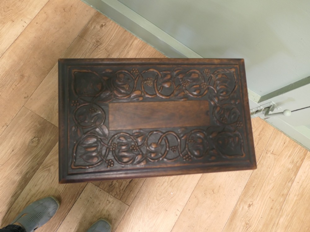 A dark carved oak joint stool featuring a carved rectangular top, a deep fluted apron with a keyhole, turned baluster legs, and lower stretchers. View VII