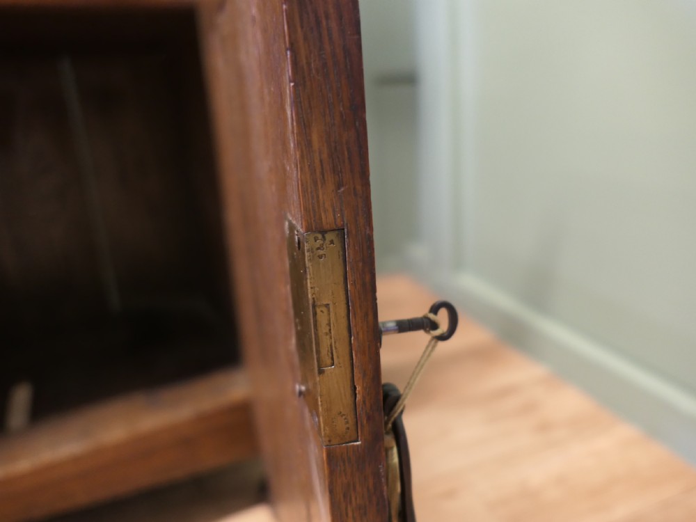 A large Arts and Crafts oak sideboard featuring a mirrored back, upper leaded glass cabinets, carved lower cupboard doors with botanical motifs, and brass handles. View V