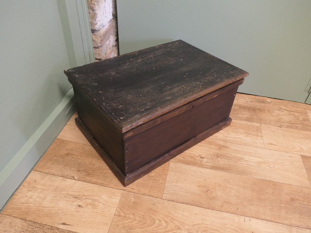 A rectangular dark stained pine carpenters box with a hinged lid and a moulded plinth base. View II