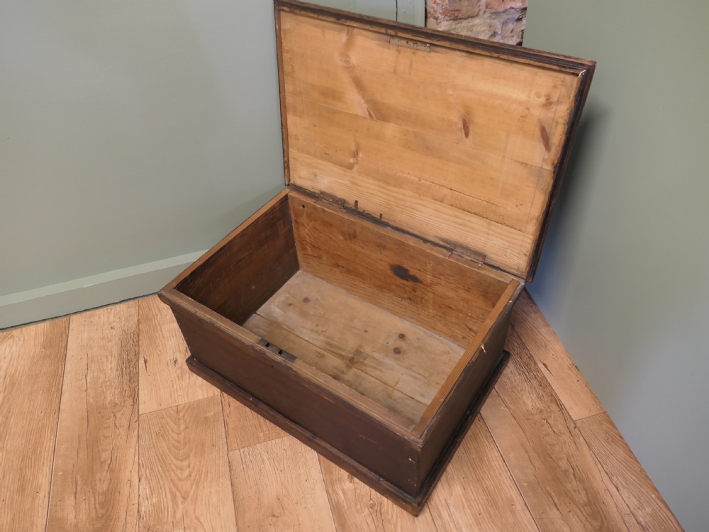 A rectangular dark stained pine carpenters box with a hinged lid and a moulded plinth base. View V