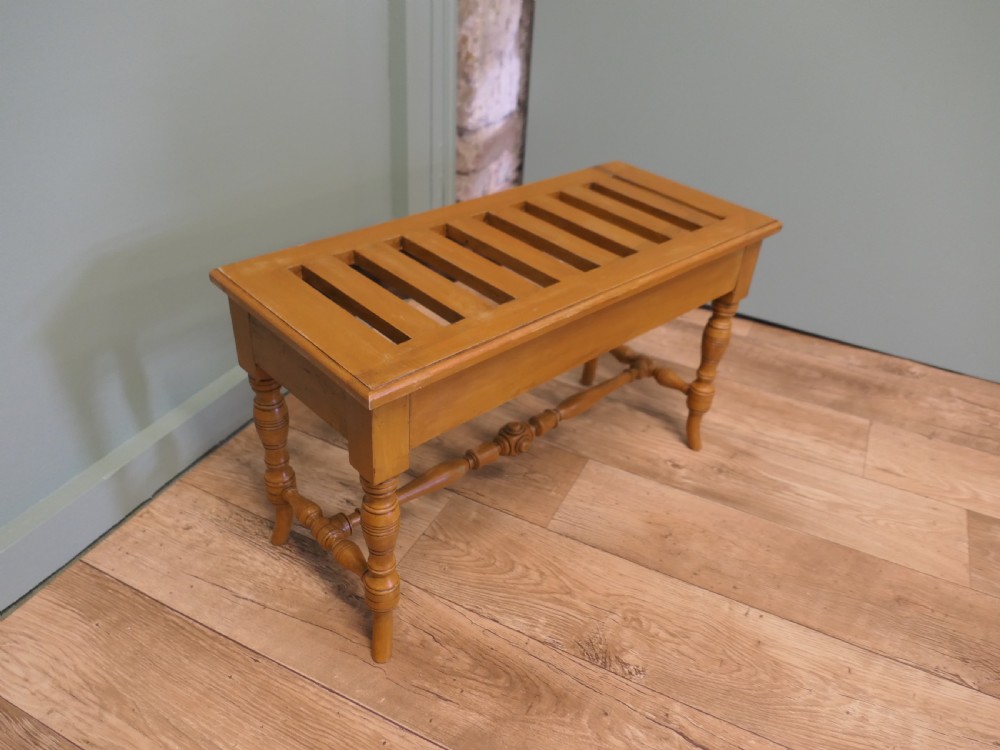 A golden oak Arts and Crafts luggage rack featuring a slatted top surface, turned legs, and a turned central stretcher. View II