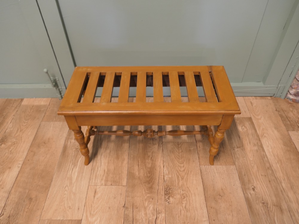 A golden oak Arts and Crafts luggage rack featuring a slatted top surface, turned legs, and a turned central stretcher. View III