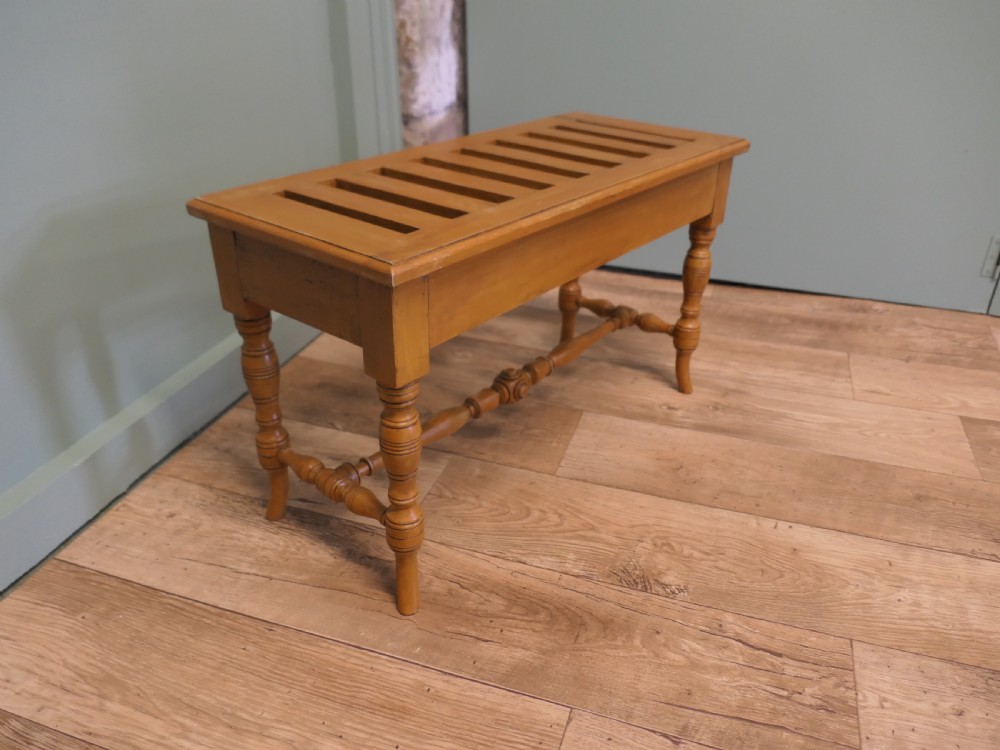 A golden oak Arts and Crafts luggage rack featuring a slatted top surface, turned legs, and a turned central stretcher. View V